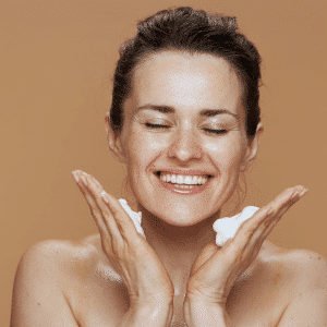 Femme de 40 ans qui sourit se mettant de la crème sur le visage